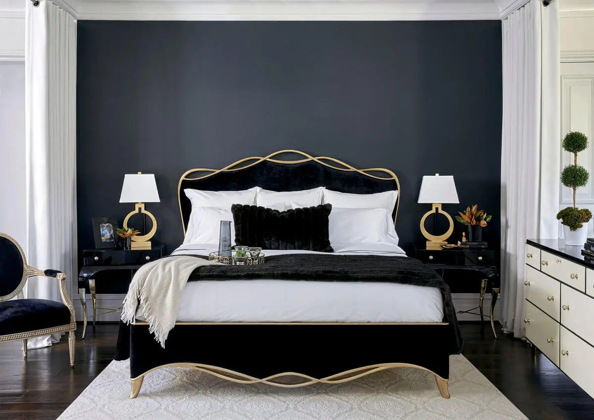 Transitional bedroom furnished with a black ribbon bed by Caracole in a black velvet fabric with a gold finish wood trim in a ribbon like form.