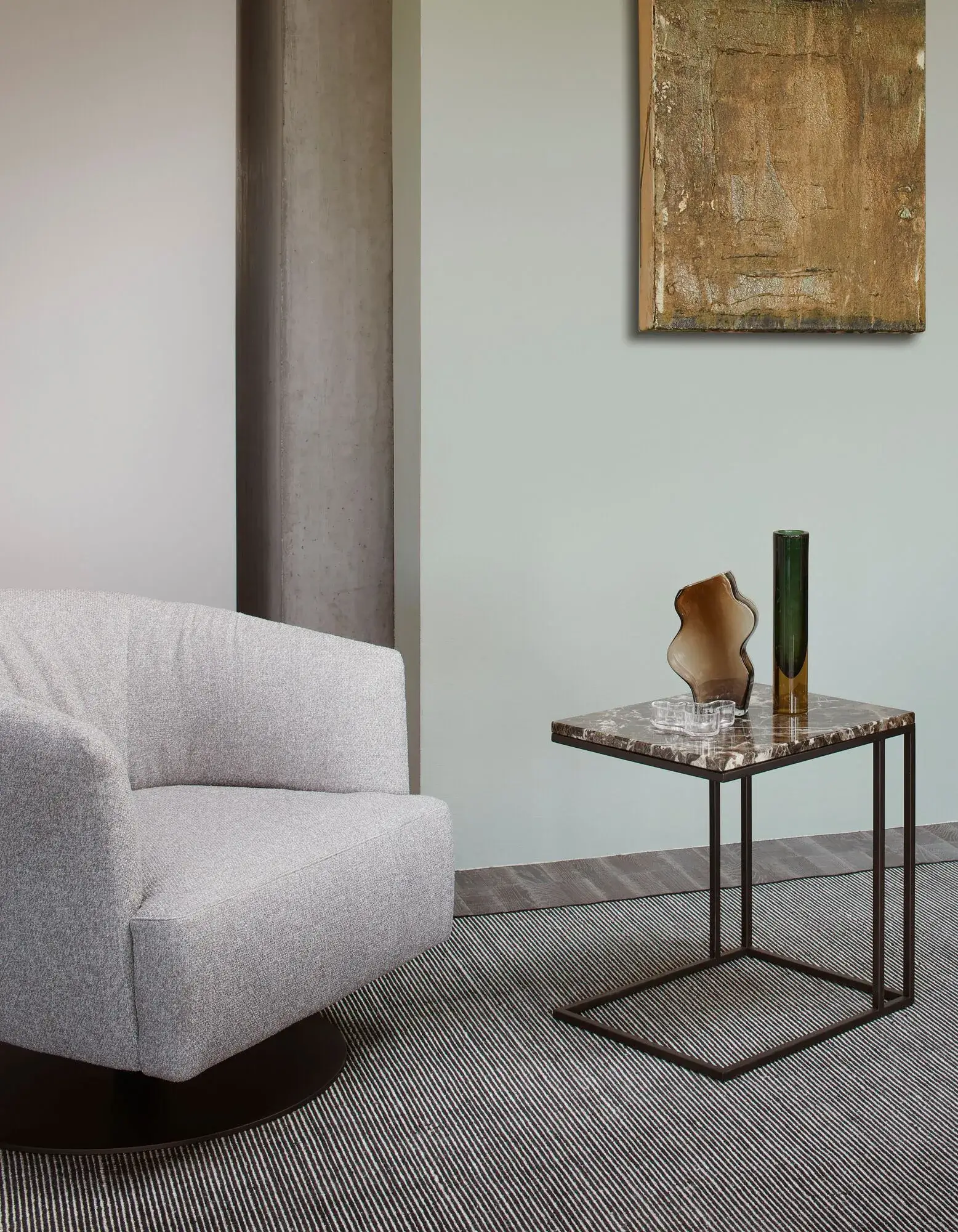gray fabric snug looking circular swivel arm chair on round black base in an empty room against a mint wall.