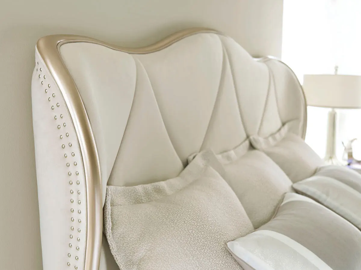detail closeup of curved cream headboard with metal nailheads