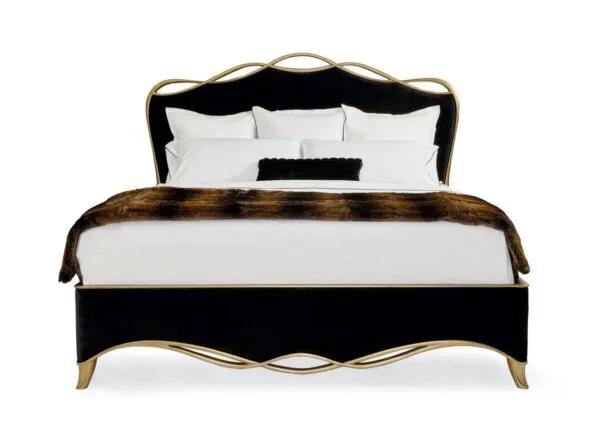 The black ribbon bed by Caracole in a black velvet fabric with a gold finish wood trim in a ribbon like form.